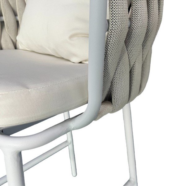 Side view of woven-rope back and thick cushion on white outdoor bar chair; removable cover and supportive wraparound arms.