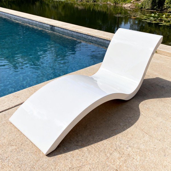 Sleek white pool chaise lounge with modern S-curve silhouette placed beside a swimming pool; smooth surface, low profile, ideal for tanning ledges and decks.