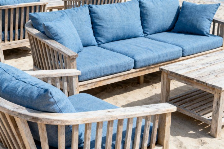 coastal outdoor furniture style with light teak and blue cushions