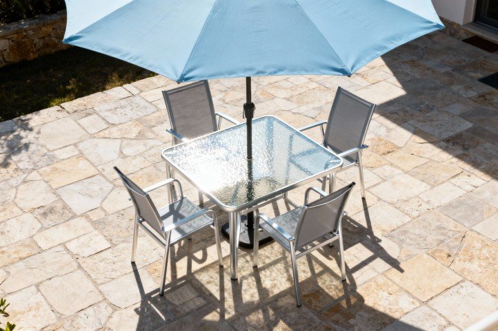 patio umbrella shading aluminum dining set at midday